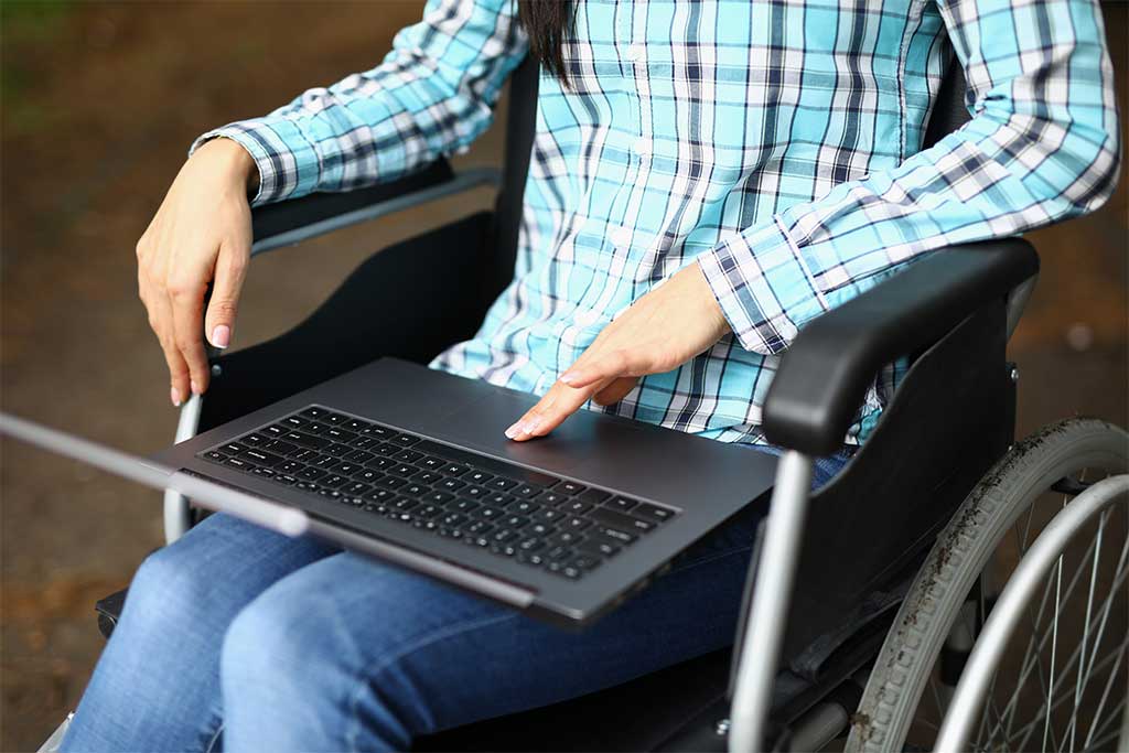 Person in a wheelchair holding a laptop